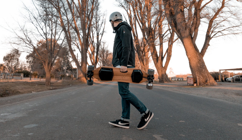 carrying electric skateboard across the road